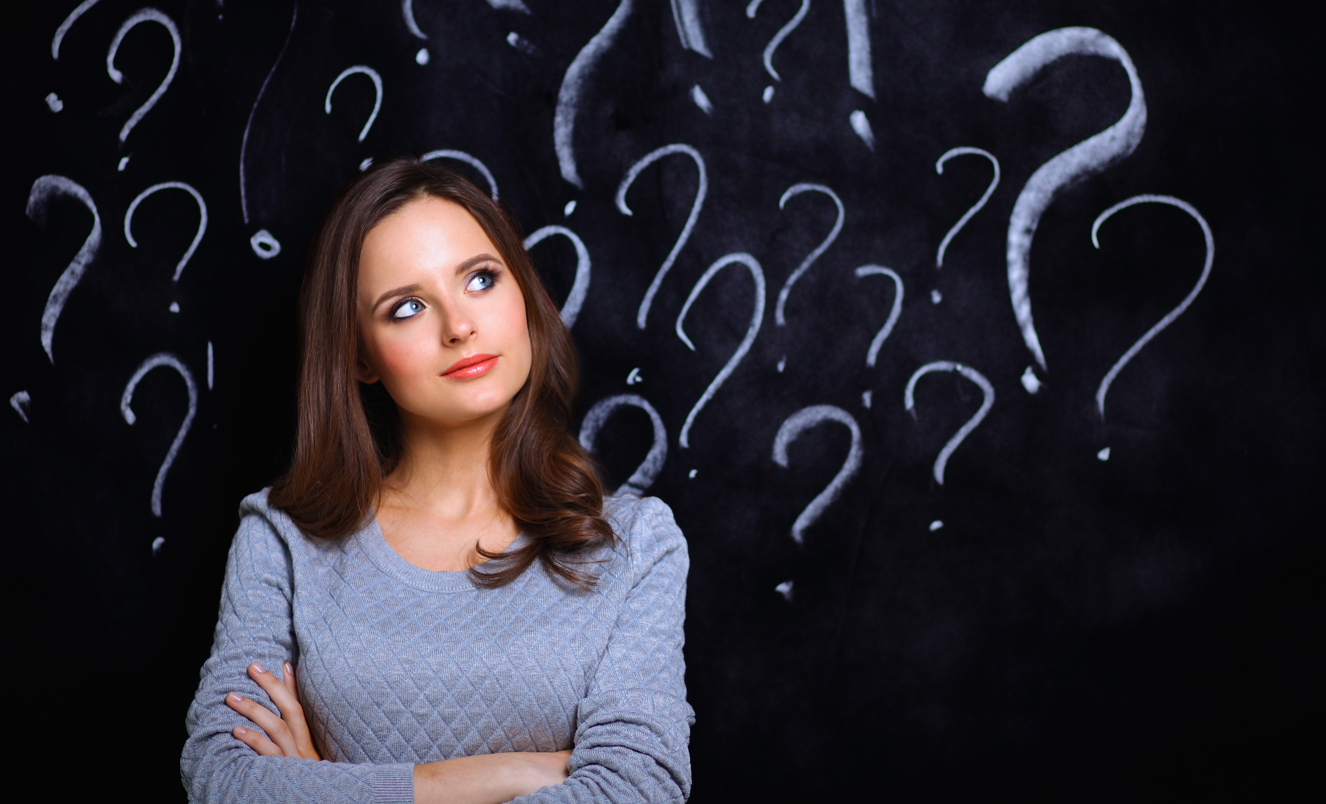 Young girl with question mark on a gray background .
